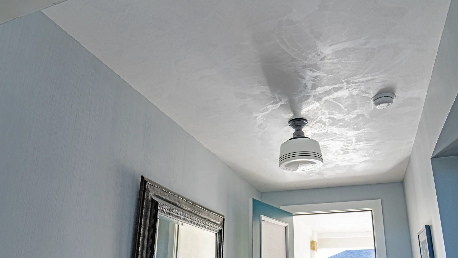 Burnished Marmorino ceiling in a white entry hall, trowel movement catching the light