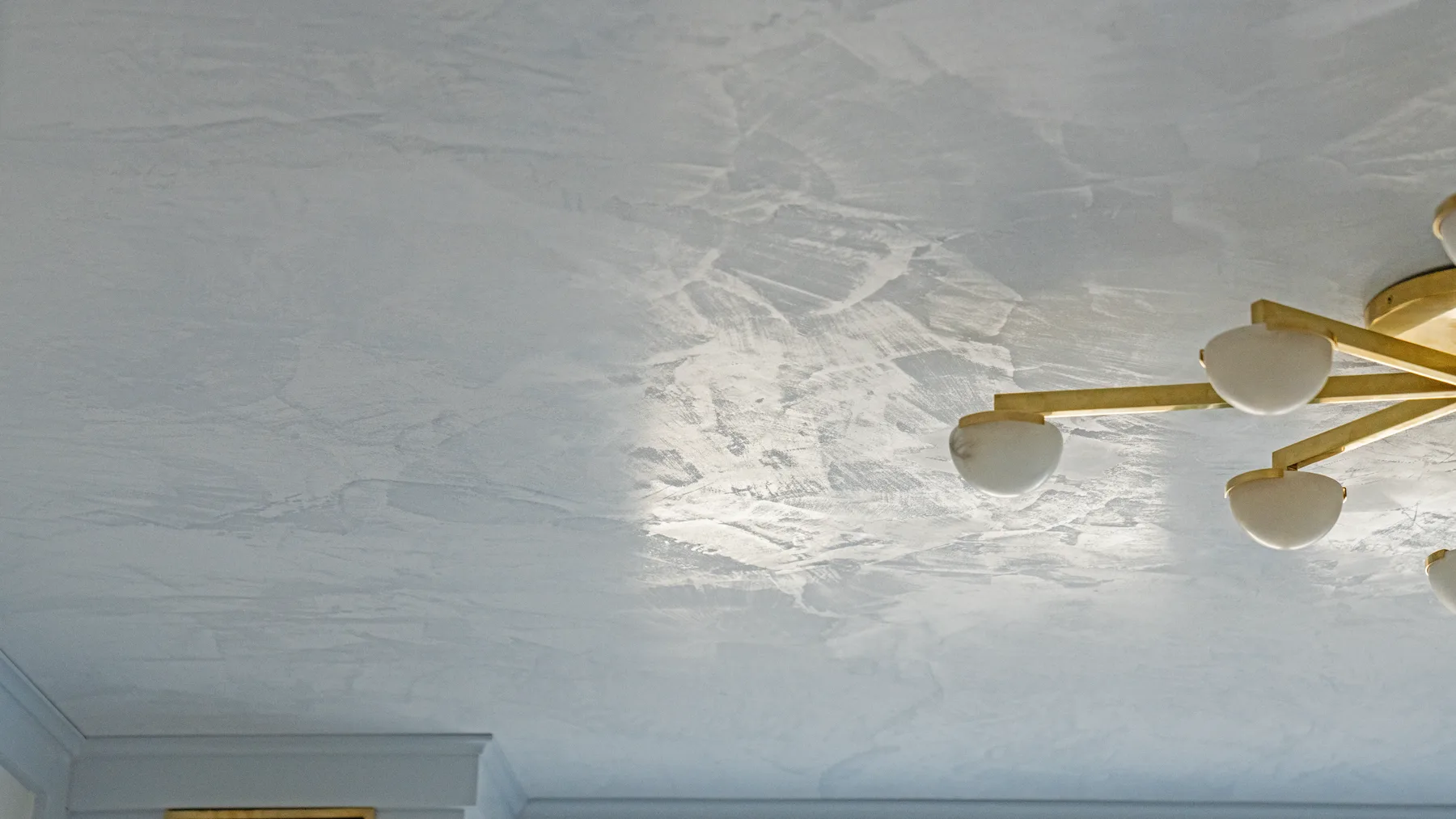 Burnished Marmorino ceiling in a small library, brass fixture against the plaster
